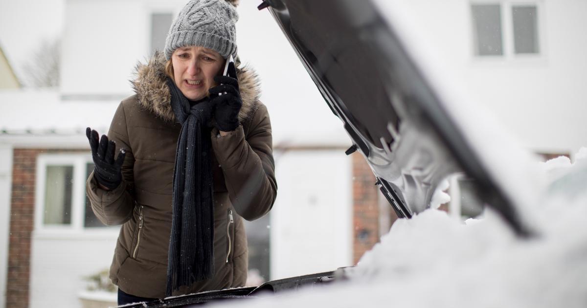 distraught woman talking on phone with car hood up