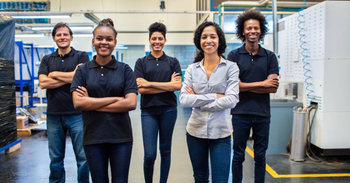 smiling manufacturing staff standing with arms crossed on production floor