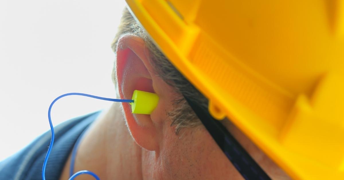 man wearing earplugs to protect hearing at work