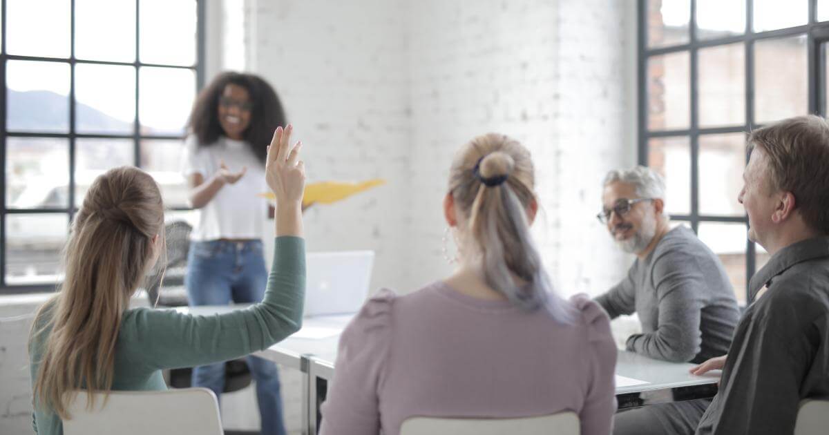 person raising hand with question in meeting